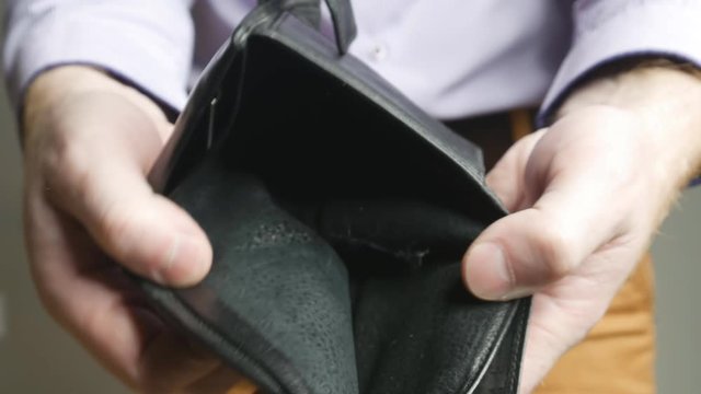 a man in trousers and shirt pulls his wallet out of his pockets, shows the frame that the wallet is empty. He shakes it and throws it on the floor. Crisis and debt. 4K