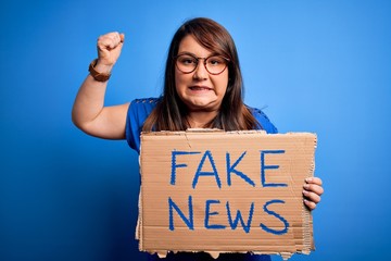 Beautiful plus size woman holding fake news banner for false journalism over isolated background...