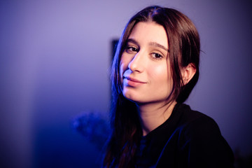 A young beautiful girl is quarantined in an apartment. Low key and blue background