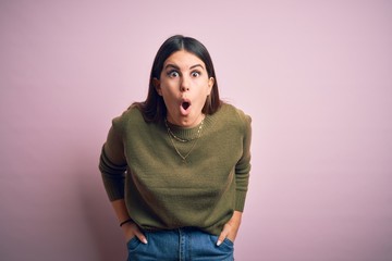 Young beautiful woman wearing casual sweater standing over isolated pink background afraid and shocked with surprise expression, fear and excited face.