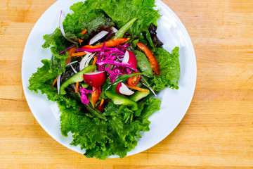 Various fresh mix salad leaves with tomato in bowl on wooden background