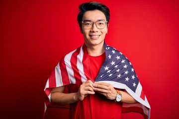 Young chinese patriotic man wearing united states of america flag over red background with a happy face standing and smiling with a confident smile showing teeth