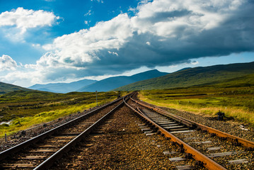 Fototapeta premium Train tracks vanish into rolling green hills