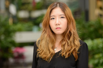 Obraz premium Face of young beautiful Asian businesswoman at the park