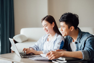 Obraz premium Young Asian couple at home using computer