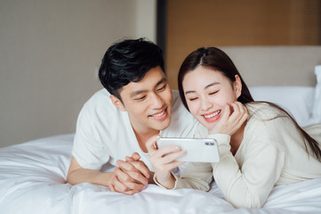 Young Asian couple at home using a smartphone