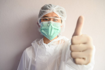 Nurse wearing PPE suit with mask for protect virus and showing thumbs up. In coronavirus pandemic...