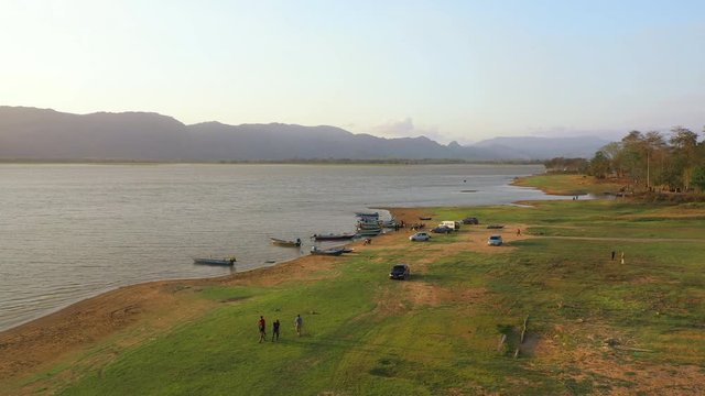 February 29th, 2020 - Perlis, Malaysia : 4k Aerial View of Unidentified people enjoying beautiful sunset at Timah Tasoh Lake Side with Mountain View . Establishing , Drone Tracking Left