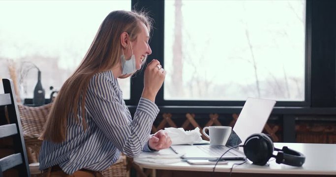Side view young healthy happy woman making video call on laptop to chat with friends from home with face mask on neck.