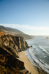 Aerial drone view of the Big Sur coastline in California. Beautiful golden light hitting the side of the cliffs at sunset along the coastal road.