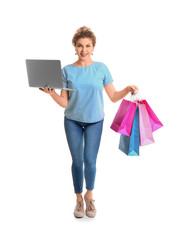 Beautiful young woman with laptop and shopping bags on white background