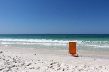 beach chair on beach facing ocean with waves and blue sky background horizon