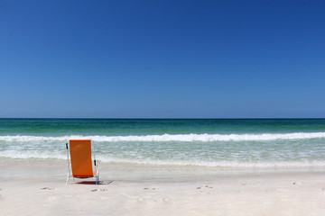 beach chair on beach facing ocean with waves and blue sky background horizon