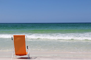 beach chair on beach facing ocean with waves and blue sky background horizon