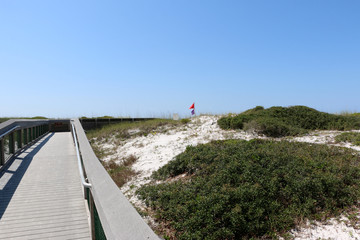 beach boardwalk over sand dunes with blue sky background at santa rosa florida state park 
