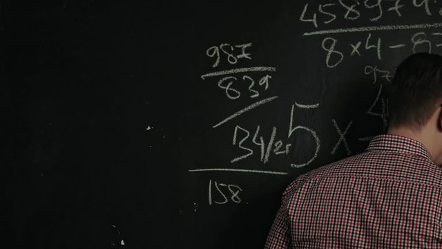 man writes math formula on blackboard