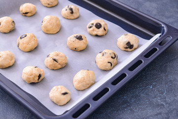 Baking tray with uncooked cookies on dark background