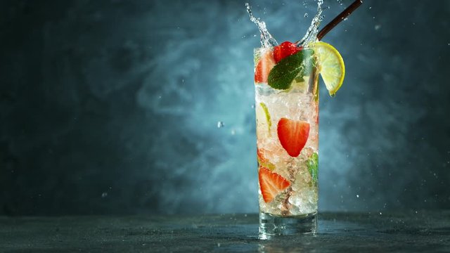 Refreshing strawberry mojito cocktail in a glass on black stone table, macro super slow motion filmed on high speed cinematic camera.