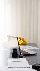 working on the laptop. the laptop is on the table. fruit in the background. home furnishings. work at home
