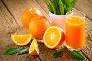 Close-up of Glass squeezed orange juice and fresh fruits ripe cut half, slice with green leaves on old wood vintage table. Breakfast food or beverage for the morning. Concept organic healthy natural.