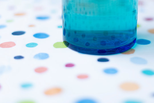 Blue Round Glass Water Jar On A Spotty Table Cloth.