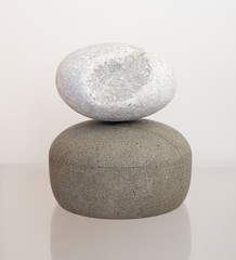 White oval pebble with a piece missing balanced on a stone pot. Smooth round stone from a beach in Skiathos.