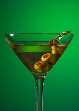 Martini And Green Olives On Knotted Bamboo Skewer. Glass Of Extra Dry Vermouth Martini. Alcohol Cocktail. Green Background. For Restaurant Menu.