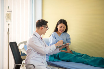 Doctor and patient discussing something while checking health in the bed at hospital © wckiw
