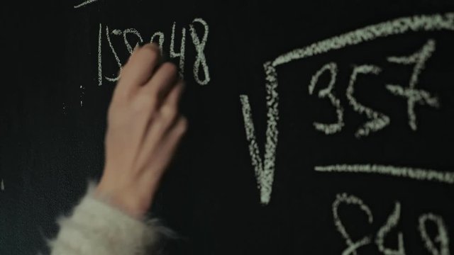 man writes math formula on blackboard