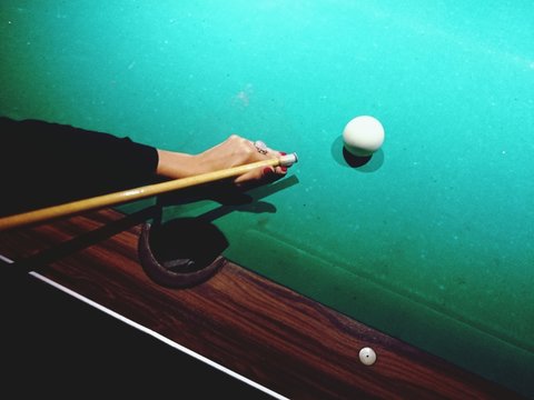 High Angle View Of Woman Aiming At Cue Ball On Pool Table