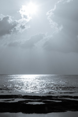 A portrait black and white shot of the Indian Ocean and rocky beach of Neil island with sun