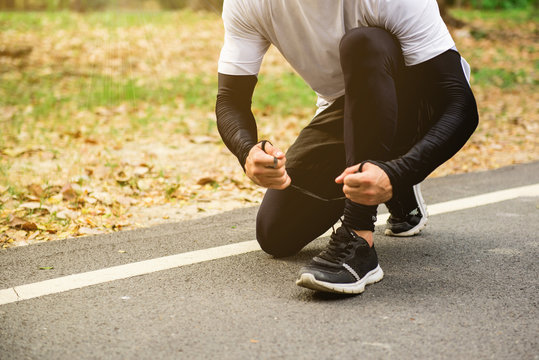 A runner man sitting and tying the shoelace before jogging