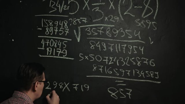 man writes math formula on blackboard