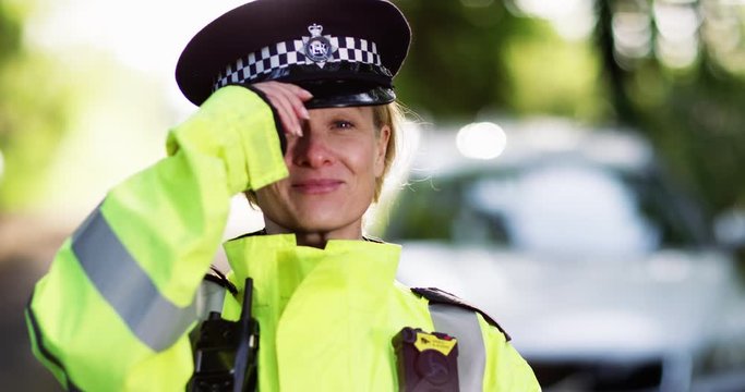 4K Close up portrait of policewoman on patrol, taking off hat & smiling at camera. Slow motion.