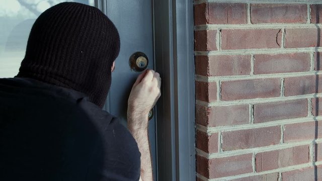 Thief attempting to pick lock on door