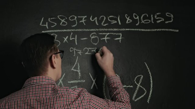 man writes math formula on blackboard