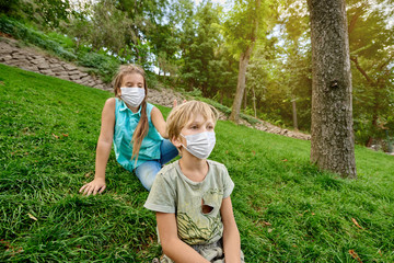 Naklejka na ściany i meble Two kids having fun and playing in the park, wearing a face mask. Flu epidemic, allergy, protection against virus. air pollution concept.