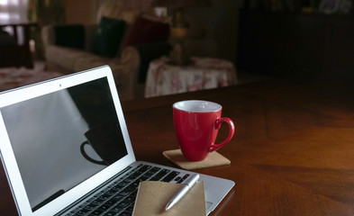 Laptop with notepad and coffee on wood table. Work at home concept.