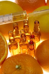 Vitamin C. glass ampoules  , syringe among the fruits of oranges and lemons on a white...