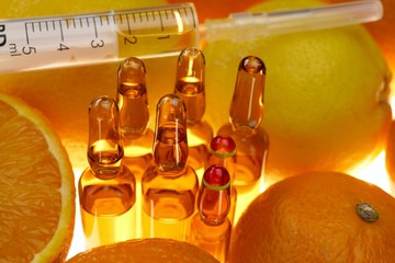 Vitamin C.  ampoules set , syringe among the fruits of oranges and lemons on a white background.prevention of immunity from viruses.Serum with Vitamin C. Organic cosmetics concept. Health 