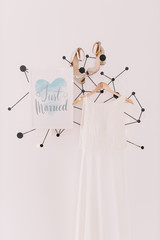 just married sign with wedding dress and shoes on white wall background