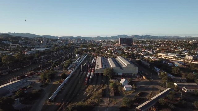 4K aerial Windhoek capital main railway station depot sheds, workshops and railway lines with trains parked area at bright sunrise drone video in Khomas Region, central Namibia