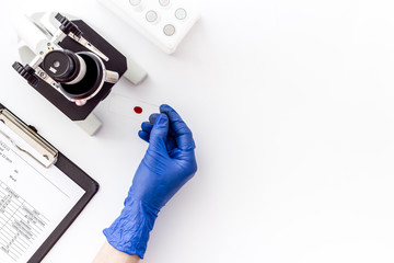 Bood testing with microscope in laboratory. Sample in hands on white background top view copy space