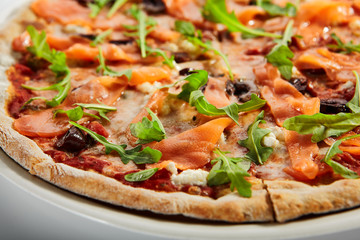 Sliced pizza with salmon, calamata olives and sun dried tomatoes