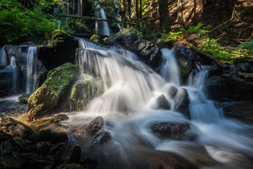 weicher wasserfall mit felsen und einer bruecke