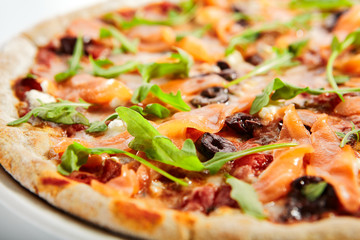 Sliced pizza with salmon, calamata olives and sun dried tomatoes
