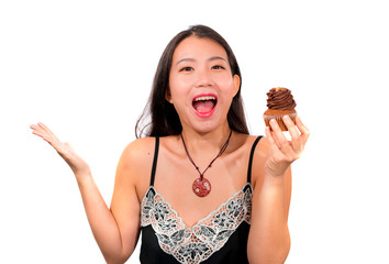 young attractive and happy Asian Chinese woman holding delicious and tempting chocolate cupcake full of calories having dilemma feeling temptation to jump her diet