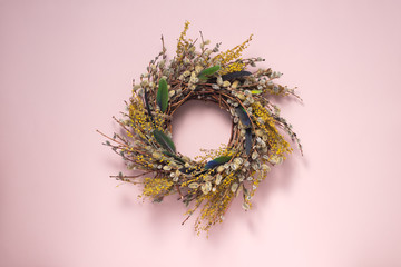 A wreath of dried twigs and flowers on a gently pink background. Natural decoration. Holiday concept. Easter wreath. Willow round frame. Postcard design concept. Copy space.
