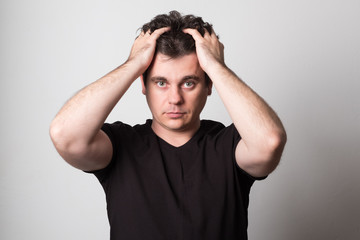 Sad man in a black t-shirt. Young man with beautiful hair. Studio image.