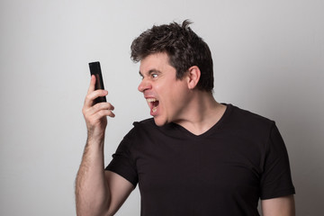 Man is talking on a cell phone. Smiling young man in a black T-shirt talking on the phone.